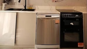 A modern kitchen with a dishwasher, oven, and a pendant light fixture.