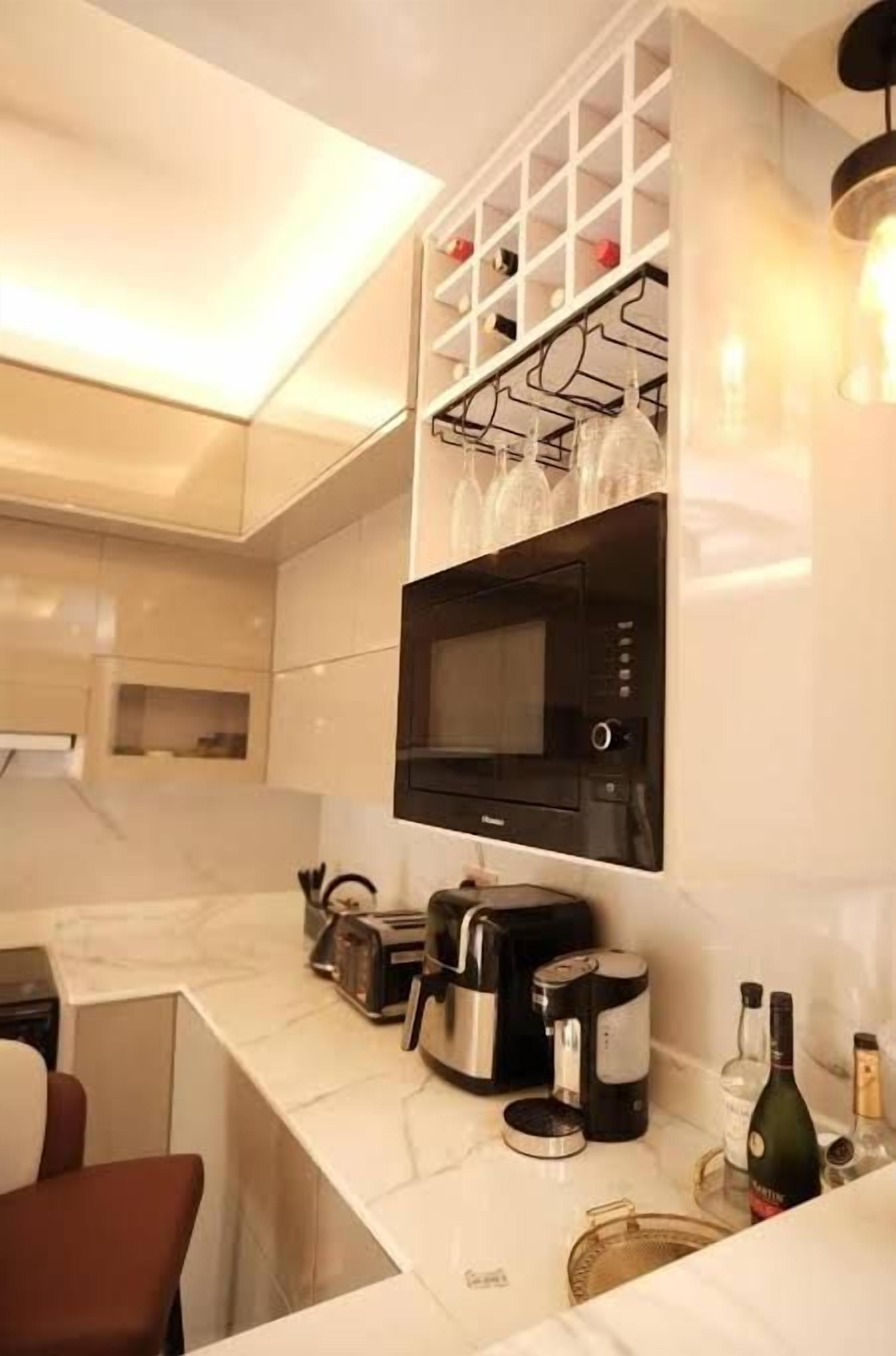 Una cocina moderna con microondas incorporado, cafetera y botella de vino.