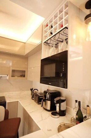 Una cocina moderna con microondas incorporado, cafetera y botella de vino.