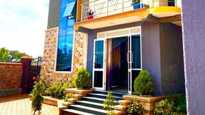 A multi-story building with a central entrance, a balcony on the upper floor, and a paved driveway.