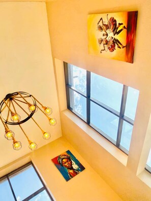 Una habitación con una lámpara en el techo, una ventana y obras de arte en las paredes.