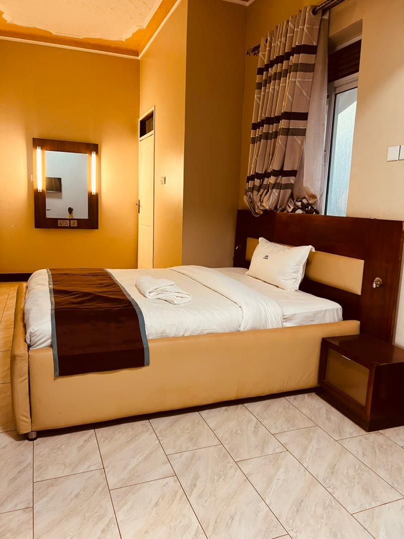 Habitación de hotel con cama, mesita de noche y un espejo en la pared.