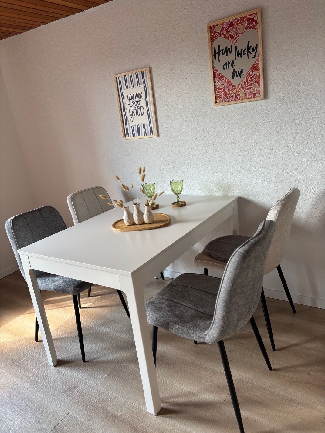 Ein Essbereich mit einem weißen Tisch, grauen Stühlen und dekorativen Vasen.