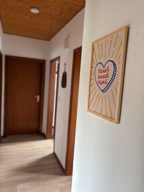 Un passadís amb portes de fusta i un rètol penjat a la paret que diu 'HOME sweet HOME'.