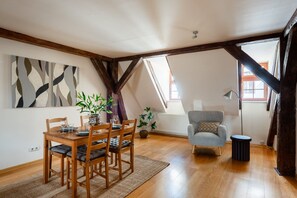 Ein Essbereich mit Holztisch und Stühlen, einer Topfpflanze und einem modernen Sessel.