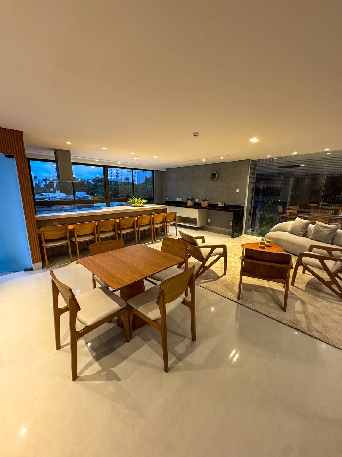 Cozinha moderna com área de refeições, sofás e vista para a paisagem urbana.