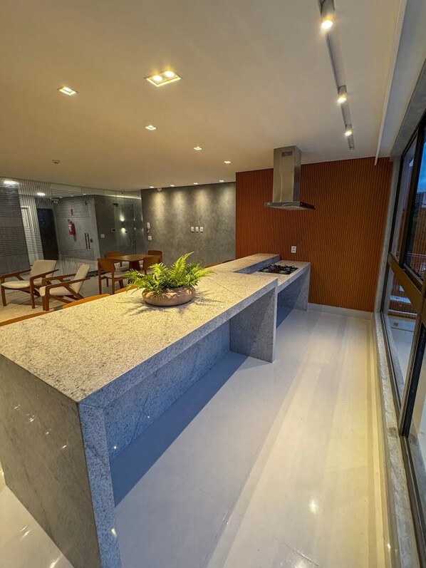 Cozinha moderna com uma ilha grande, eletrodomésticos embutidos e vista para o exterior.