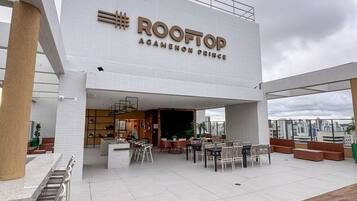 Un bar panoramico chiamato 'Rooftop' con posti a sedere all'aperto e vista sullo skyline della città.