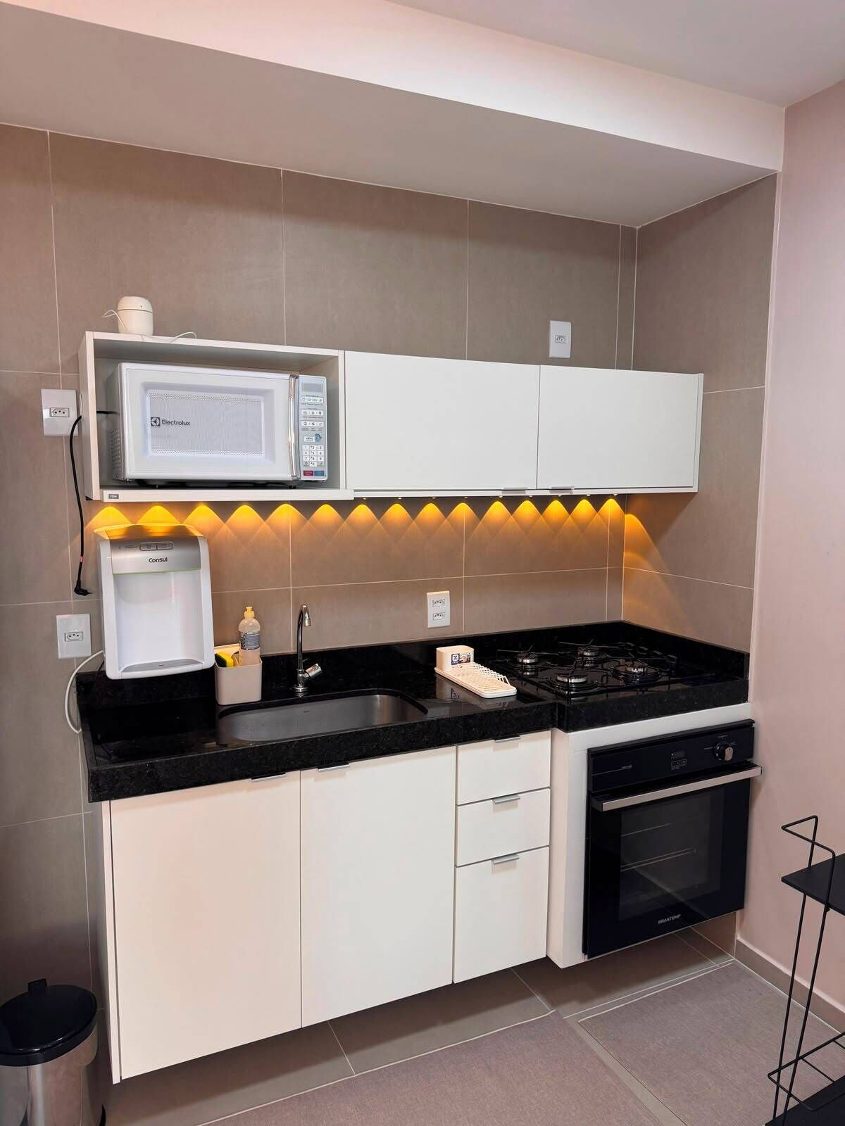 Een moderne keuken met een magnetron, fornuis en een inbouwoven.