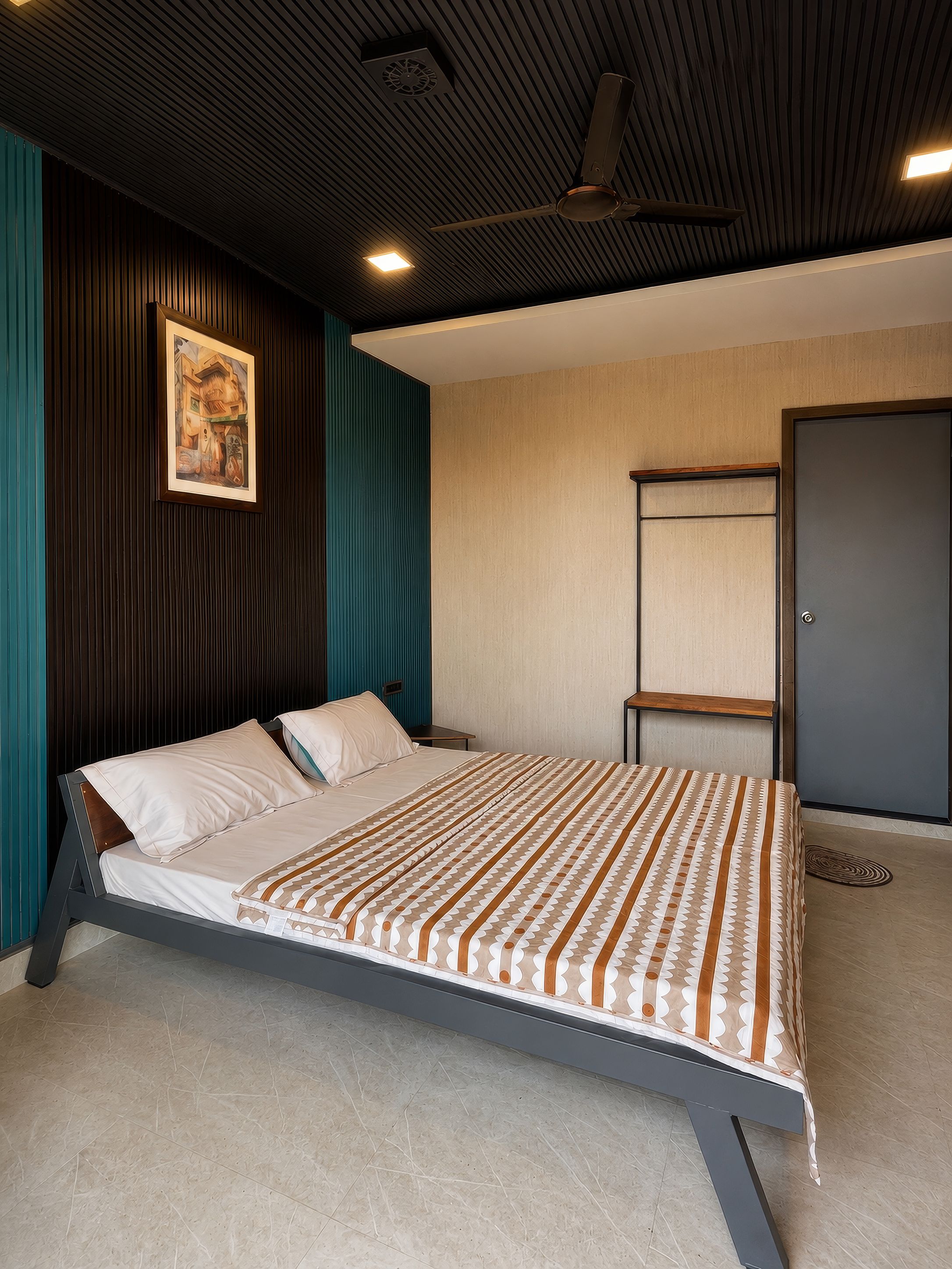 A modern bedroom with a bed, a painting on the wall, and a door.