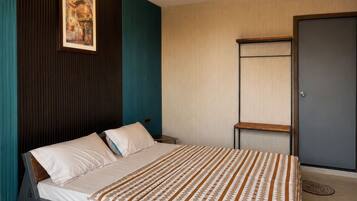 A modern bedroom with a bed, a painting on the wall, and a door.