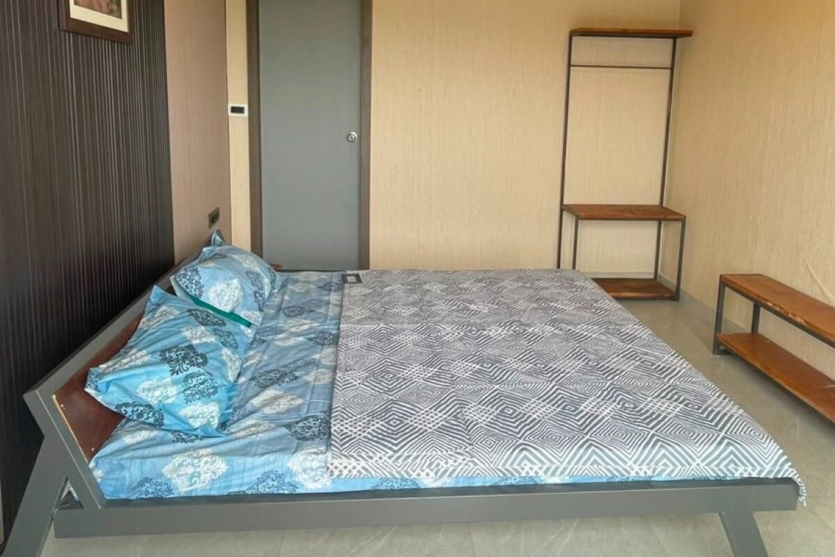 A room with a bed, a door, a bench, and a ceiling fan.