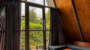 Un interior moderno con techo inclinado, ventanas grandes, un sofá y una alfombra estampada.