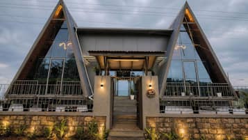 Un edificio moderno con fachada triangular, ventanas amplias y base de piedra.