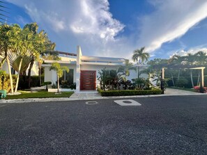 A modern building with a flat roof, a red door, and a paved driveway. - Sosua Ocean Village - Las Palmas Villa #4 (Sosúa)