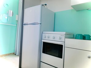 Uma cozinha compacta com geladeira, forno e fogão brancos.