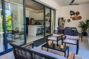 A modern interior with a dining area, kitchen, and a sliding glass door leading to an outdoor space. - Poolside 2 Bedroom Apartment (Las Terrenas)