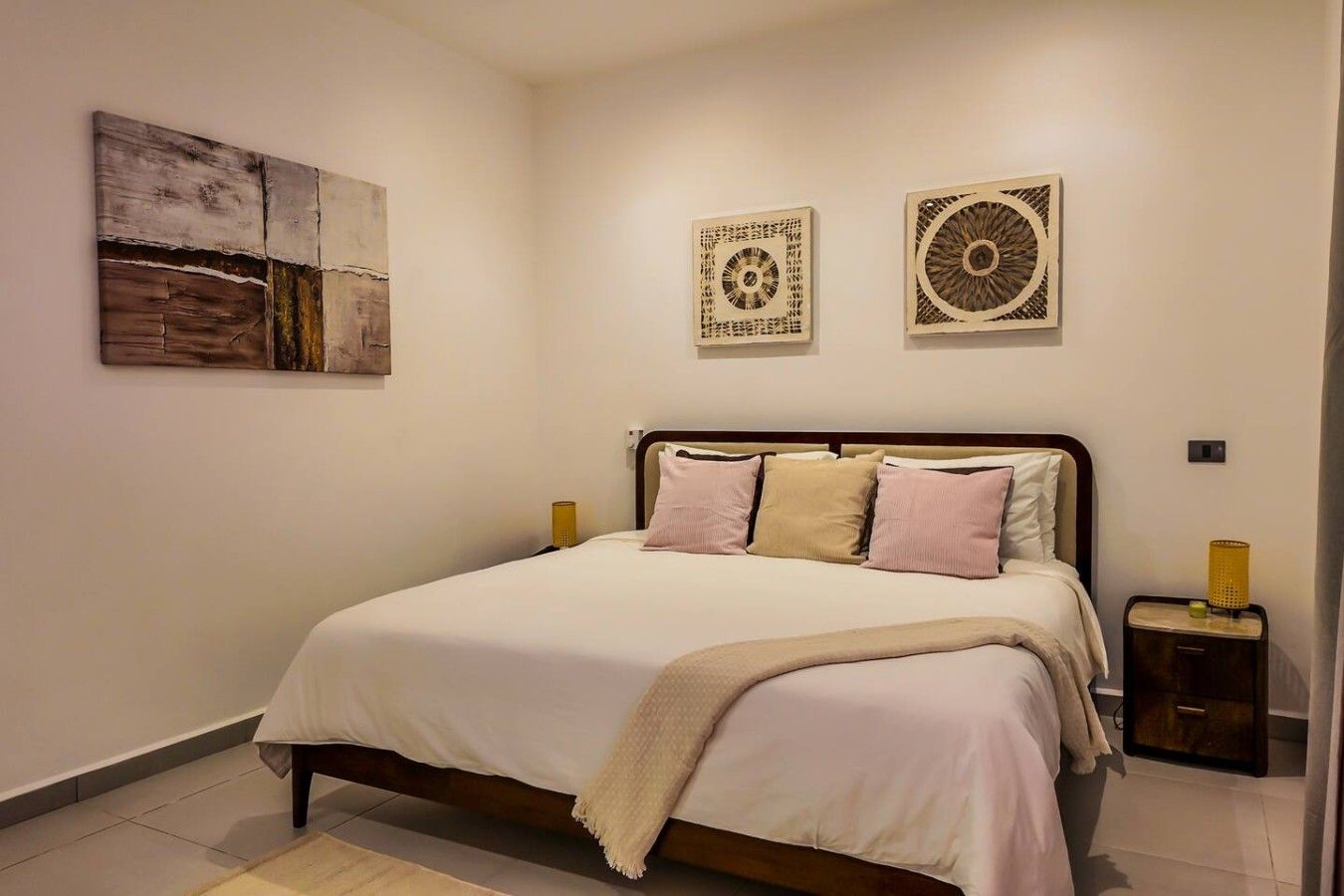 A bedroom with a bed, bedside tables, and wall art.