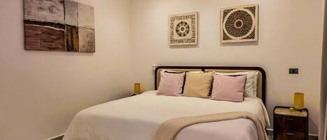 A bedroom with a bed, bedside tables, and wall art.