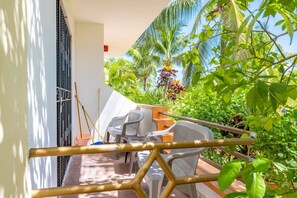 Un balcon agrémenté d’une table et de chaises, entouré d’une végétation luxuriante et de palmiers.