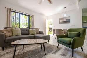 Un salon moderne avec un canapé d’angle, un fauteuil vert et une table basse.