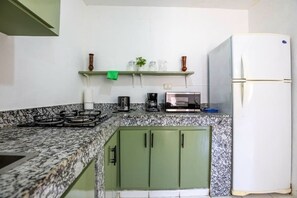 A kitchen with granite countertops, a gas stove, a microwave, and a refrigerator. - One Bedroom Central Apartment (Sosúa)