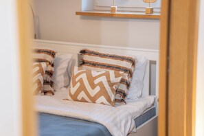 A bed with white bedding and two patterned pillows.