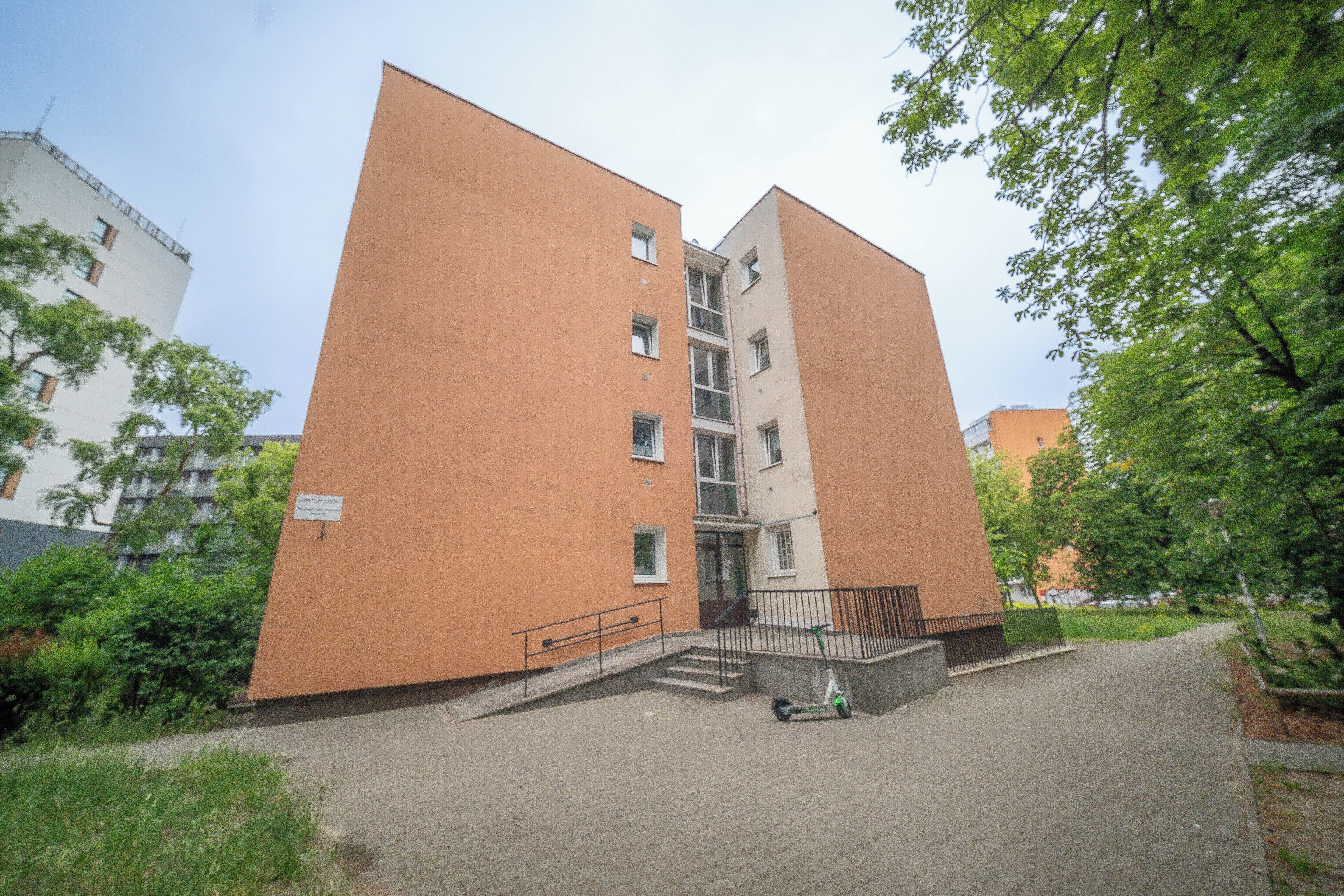 Un immeuble à plusieurs étages, doté d’une façade plane, d’un escalier central et d’un espace d’entrée pavé.