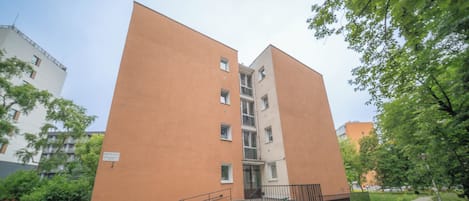 Un edificio de varios pisos con fachada plana, una escalera central y un área de entrada pavimentada.