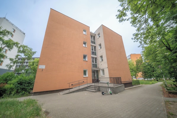A multi-story building with a flat facade, a central staircase, and a paved entrance area.