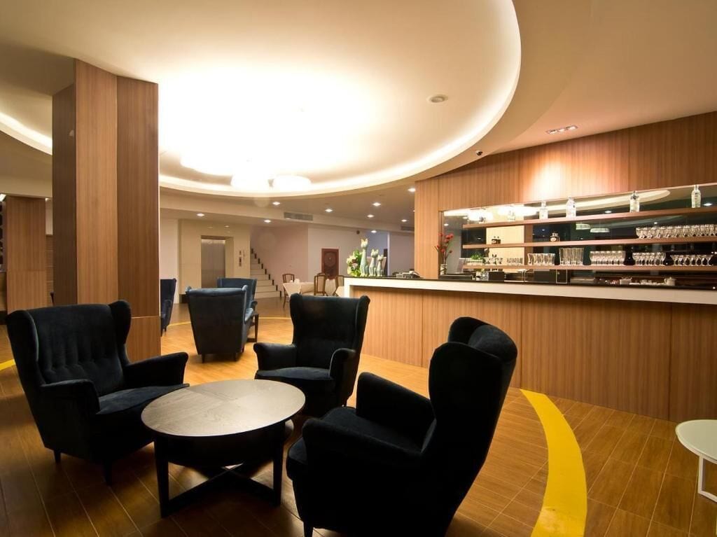 Un vestíbulo moderno con zona de bar, asientos y una escalera al fondo.