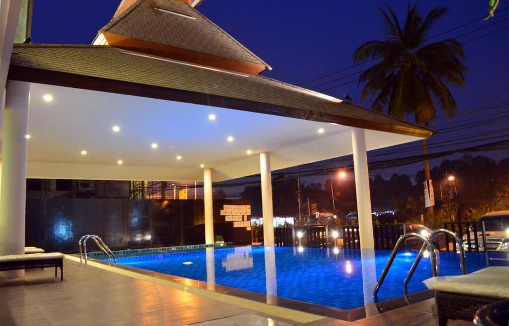 Una piscina interior con área techada, asientos y una palmera al fondo.