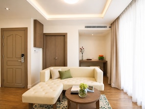 A modern living room with a sofa, ottoman, and a coffee table with a vase.