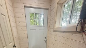 A narrow hallway with a white door, wooden walls, and a radiator.