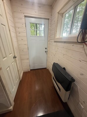 Un couloir étroit avec une porte blanche, des murs en bois et un radiateur.
