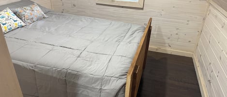 Une petite pièce agréable, avec un lit simple, une fenêtre et un plancher en bois.