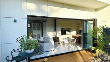 A modern house with a patio area featuring a dining table, chairs, and potted plants.