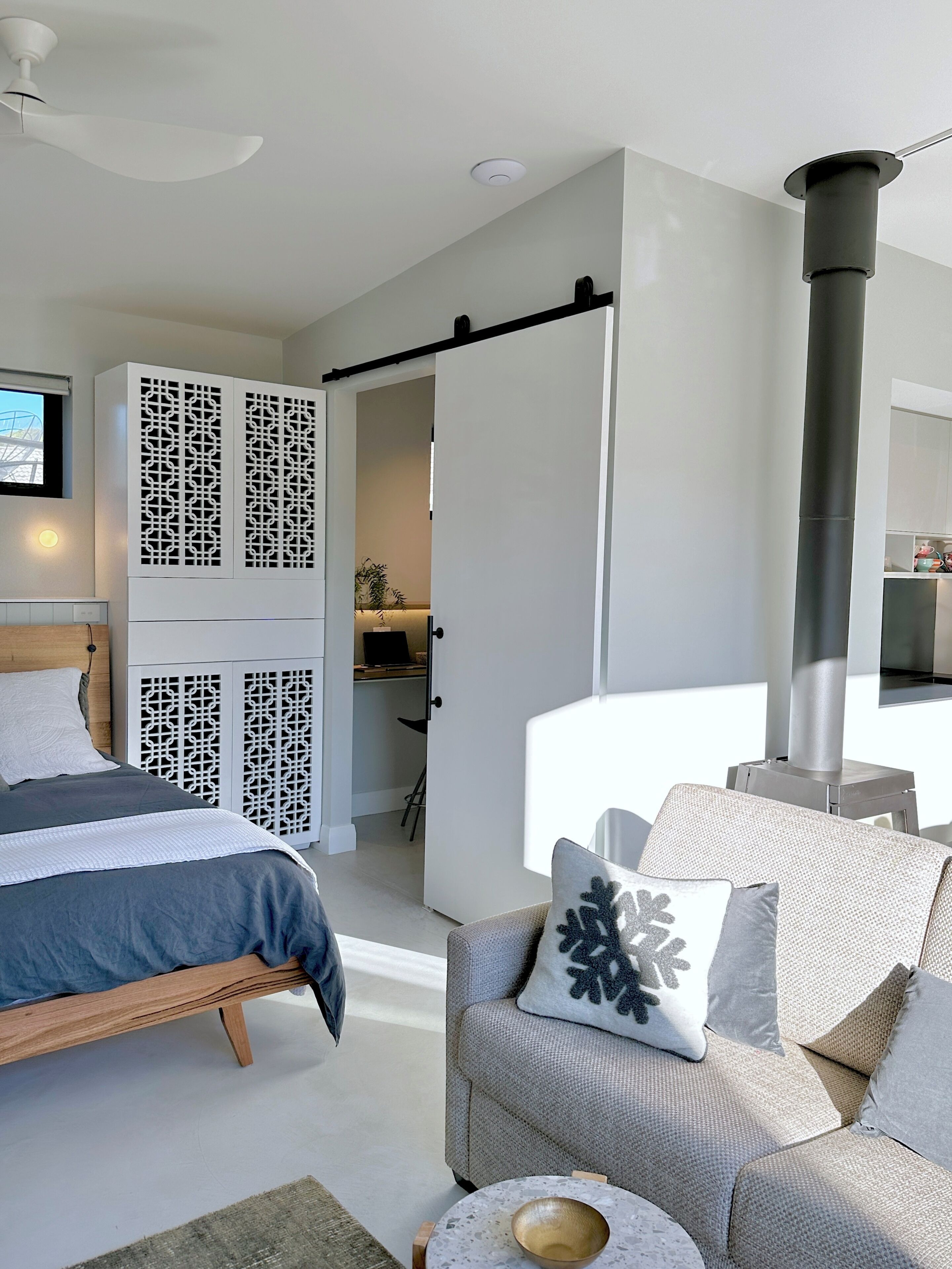A modern bedroom with a bed, a sofa, a coffee table, and a fireplace.