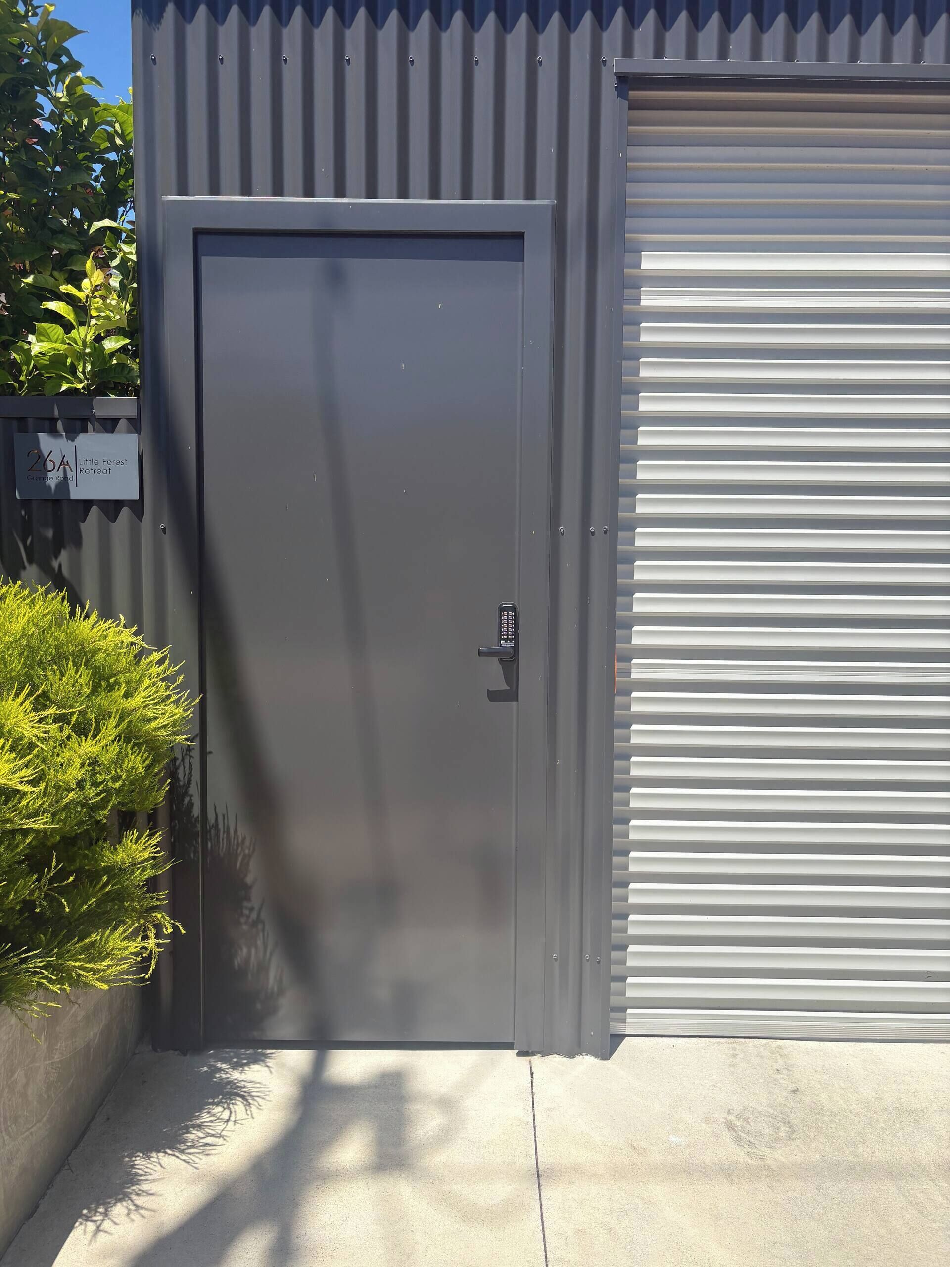 A metal door with a keypad lock, a garage door, and a sign indicating a location.