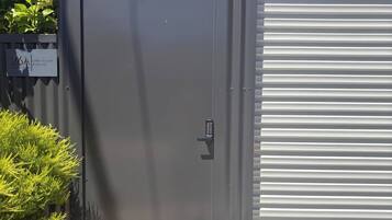A metal door with a keypad lock, a garage door, and a sign indicating a location.