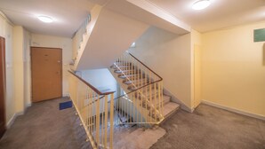 A multi-level interior with a carpeted staircase, a door, and a light fixture on the ceiling. - Yellow Vibe Złota (Warszawa)