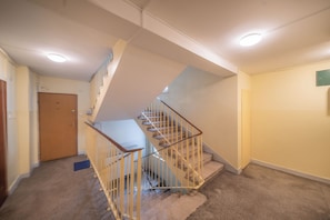 A multi-level interior with a carpeted staircase, a door, and a light fixture on the ceiling. - Yellow Vibe Złota (Warszawa)