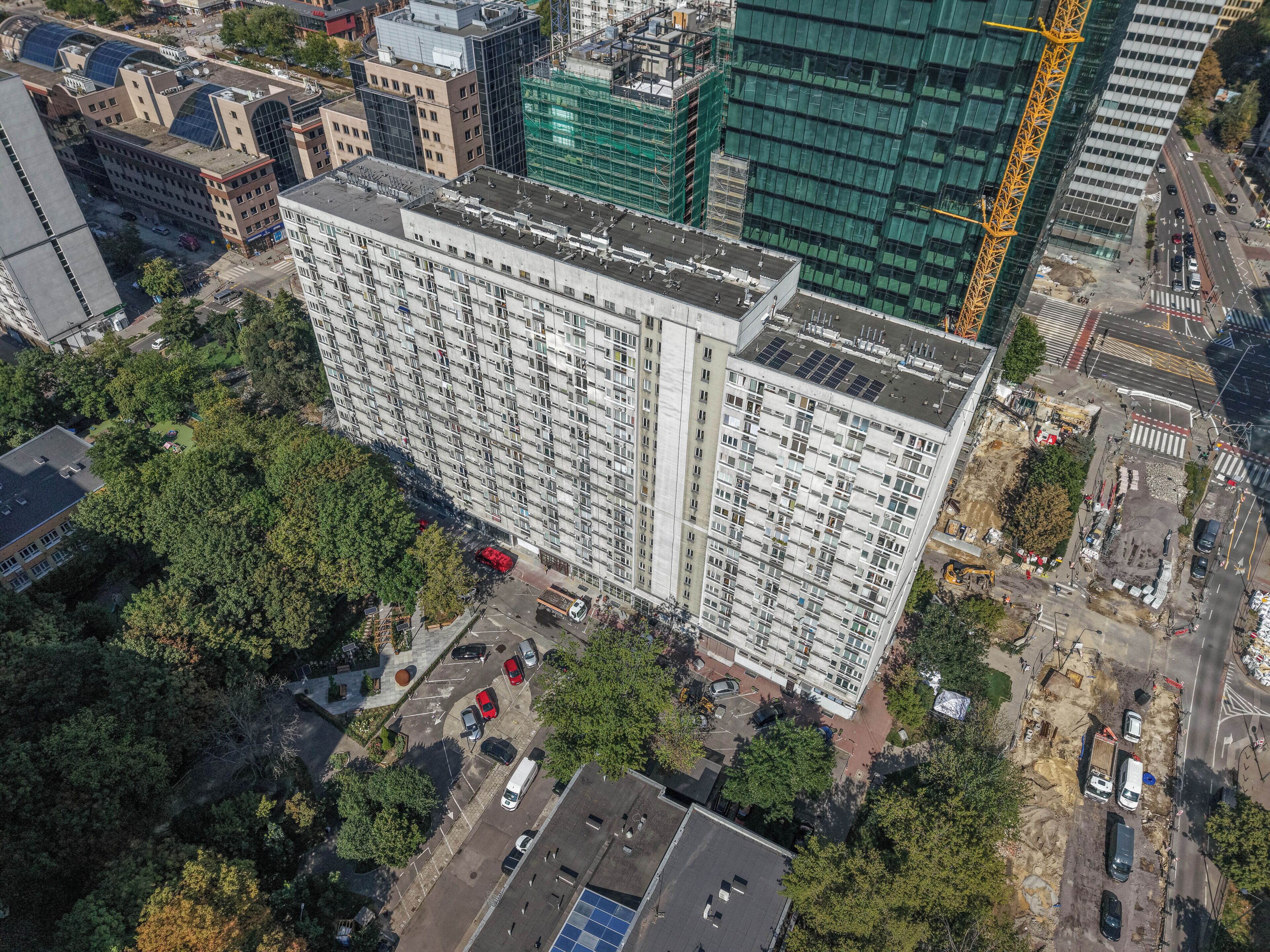 A high-rise building with multiple floors, surrounded by trees and other buildings.