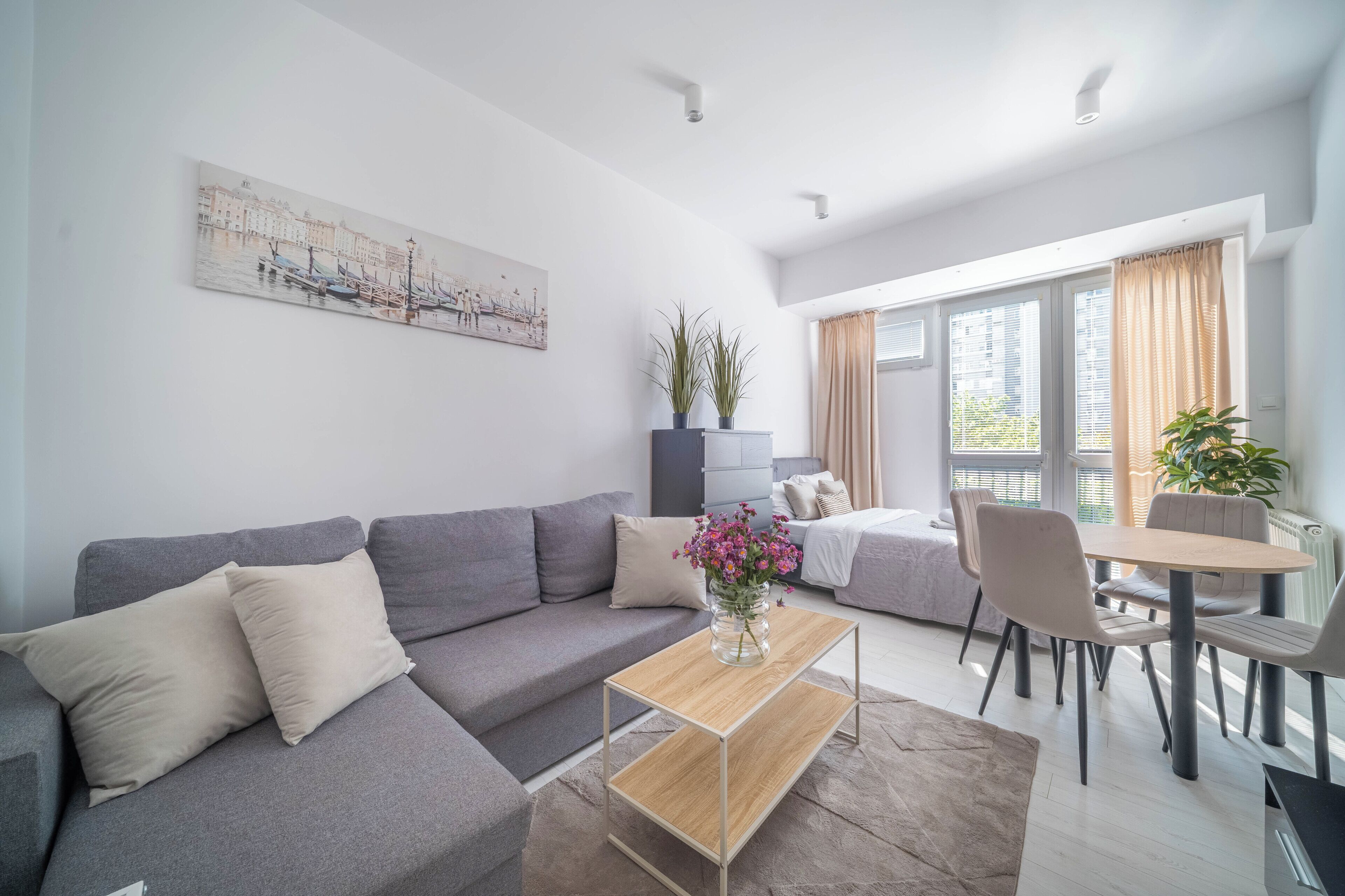 Un salon moderne avec un canapé gris, une table basse en bois et un coin repas comprenant une table et des chaises.