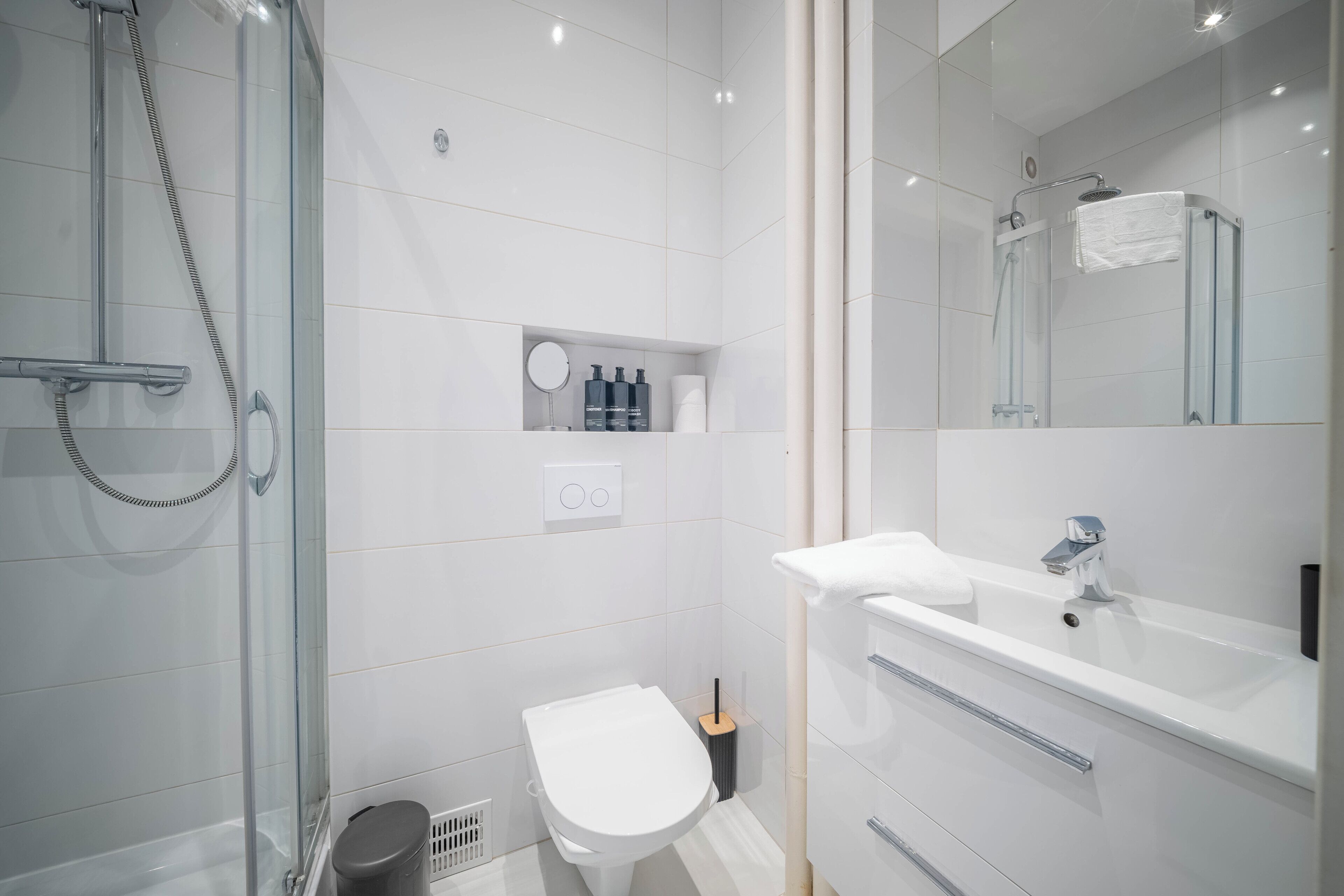 Un baño moderno con ducha envuelta en vidrio, lavamanos blanco y un inodoro.