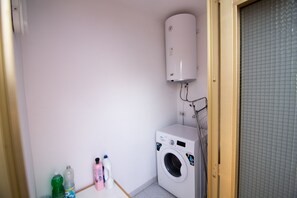 Et vaskerum med vaskemaskine og varmtvandsbeholder.