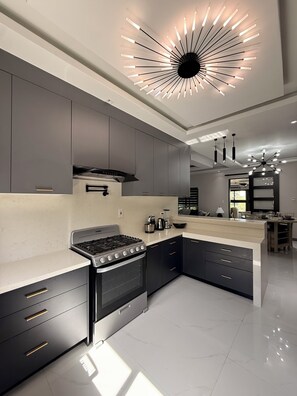 Cozinha moderna com ilha central, eletrodomésticos embutidos e luminárias contemporâneas.