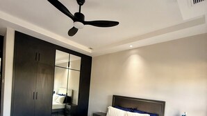 Un dormitorio moderno con cama, mesitas de noche, ventilador de techo y armario.