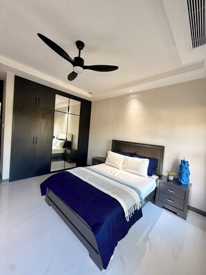 Ein modernes Schlafzimmer mit einem Bett, Nachttischen, einem Deckenventilator und einem Kleiderschrank.