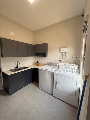 Un espace buanderie compact comprenant un lave-linge, un sèche-linge et un petit évier.